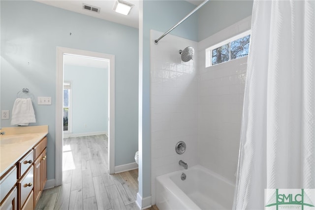 bathroom featuring shower / tub combo, visible vents, toilet, wood finished floors, and vanity