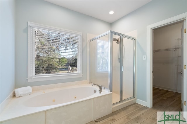 full bath with wood finished floors, a whirlpool tub, a spacious closet, a shower stall, and recessed lighting