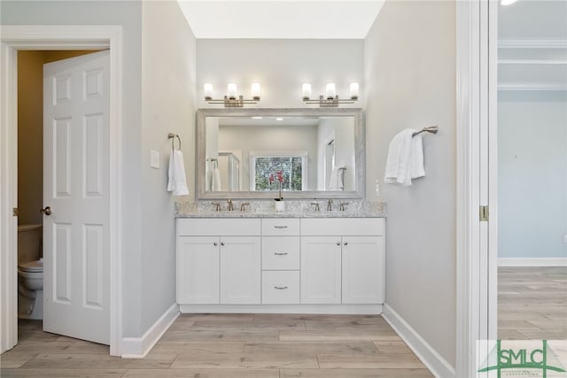 bathroom featuring double vanity, baseboards, a sink, and wood finished floors