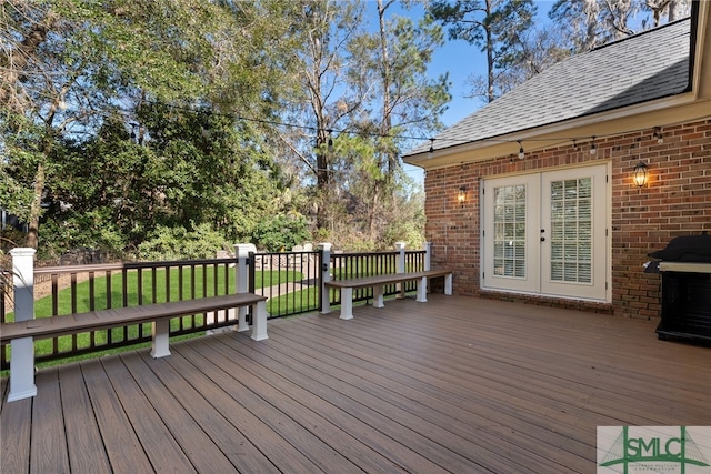 wooden terrace featuring a yard, french doors, and a grill