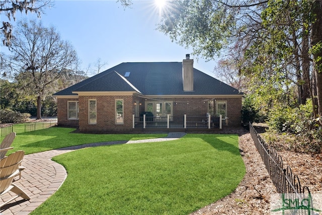 rear view of property with a patio, a chimney, fence, a yard, and brick siding