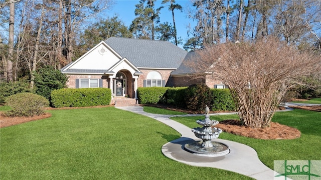 view of front of home featuring roof with shingles, brick siding, and a front lawn