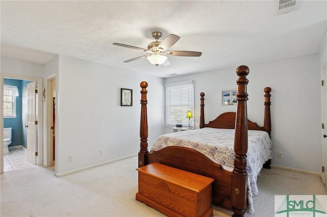 bedroom with ensuite bath, baseboards, visible vents, and light carpet