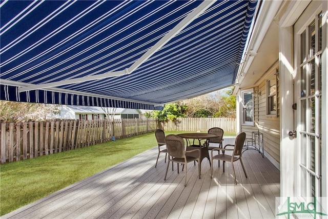 wooden deck featuring outdoor dining area, a lawn, and a fenced backyard