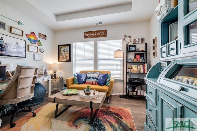 office featuring a raised ceiling, visible vents, dark wood finished floors, and baseboards