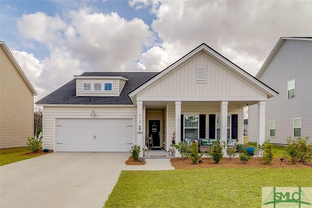 view of front of property featuring a porch, board and batten siding, a front yard, a garage, and driveway