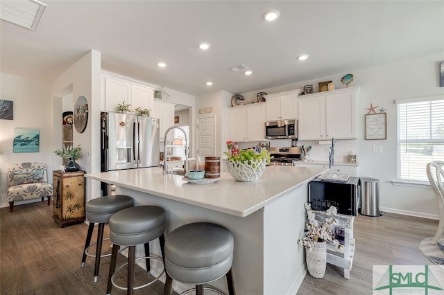 kitchen featuring appliances with stainless steel finishes, a center island with sink, a sink, and visible vents