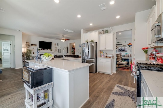 kitchen with stainless steel appliances, a sink, open floor plan, light countertops, and light wood-type flooring