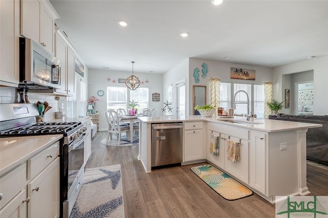 kitchen with white cabinets, appliances with stainless steel finishes, light countertops, light wood-type flooring, and a sink