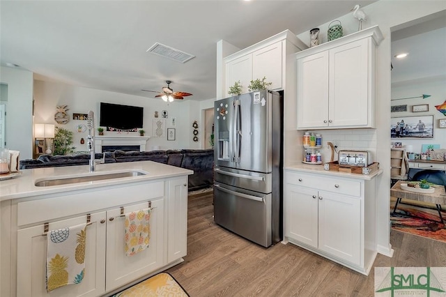 kitchen featuring a sink, visible vents, open floor plan, light wood-type flooring, and stainless steel fridge