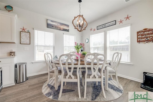 dining area featuring light wood-style floors, baseboards, and a chandelier