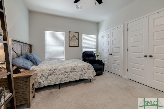 bedroom featuring carpet floors, visible vents, ceiling fan, and two closets