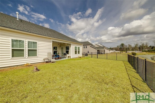 rear view of property with a fenced backyard, a yard, a patio, and roof with shingles