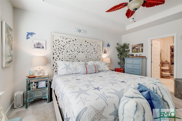 bedroom featuring a raised ceiling, carpet flooring, a ceiling fan, and baseboards