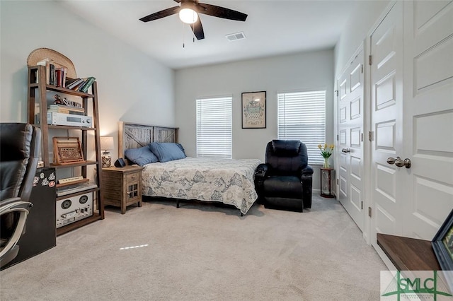 carpeted bedroom with ceiling fan, multiple windows, and visible vents