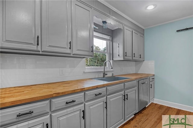 kitchen featuring crown molding, decorative backsplash, wood finished floors, wooden counters, and a sink