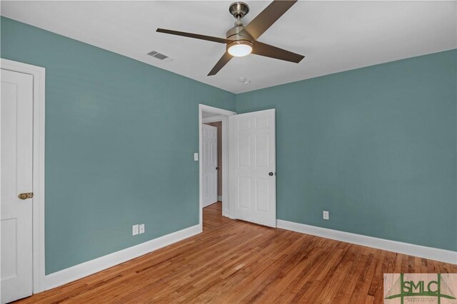 unfurnished bedroom featuring baseboards, ceiling fan, wood finished floors, and visible vents