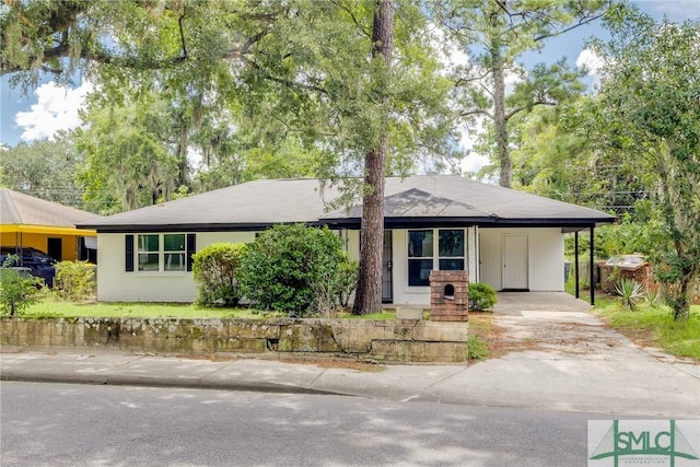 single story home featuring a carport, concrete driveway, and brick siding