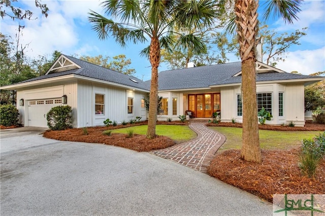 view of front facade with an attached garage, french doors, concrete driveway, and a front yard