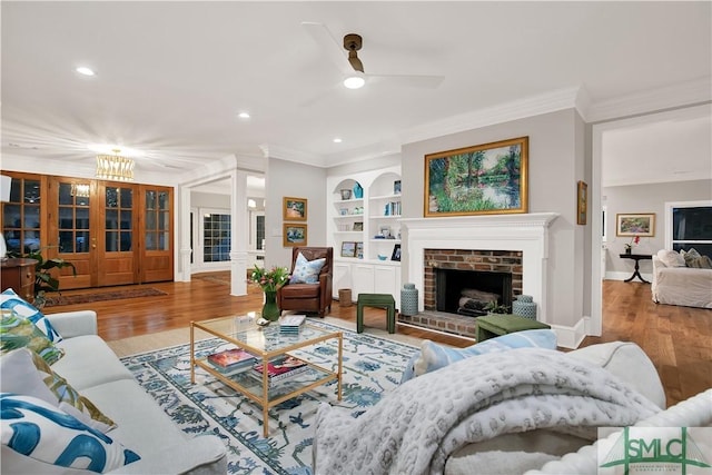 living area featuring built in shelves, a brick fireplace, crown molding, and wood finished floors