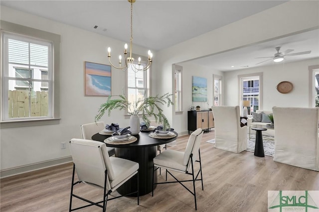 dining room with a chandelier, light wood-style flooring, and baseboards