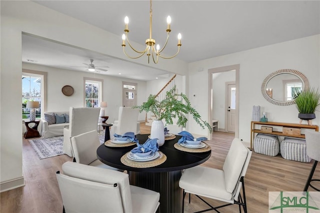 dining area featuring light wood finished floors, stairway, and an inviting chandelier