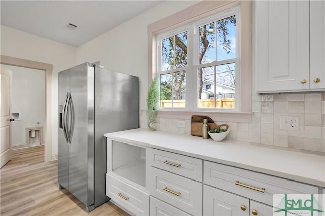 kitchen featuring tasteful backsplash, stainless steel fridge, visible vents, and white cabinets