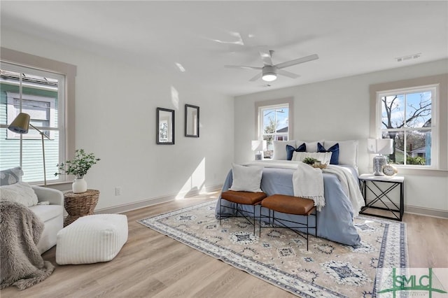 bedroom with baseboards, visible vents, ceiling fan, and wood finished floors