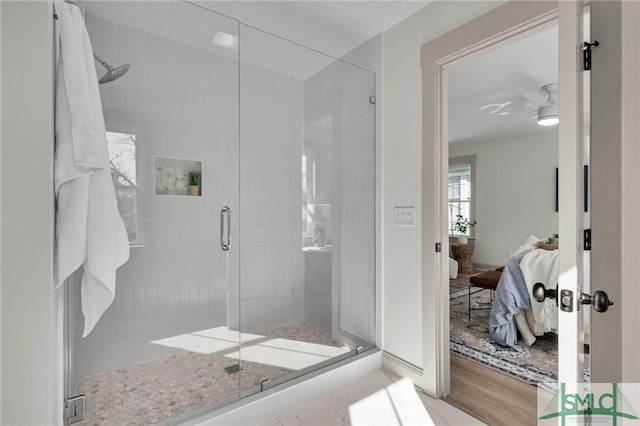 ensuite bathroom featuring a stall shower, ensuite bath, ceiling fan, and wood finished floors