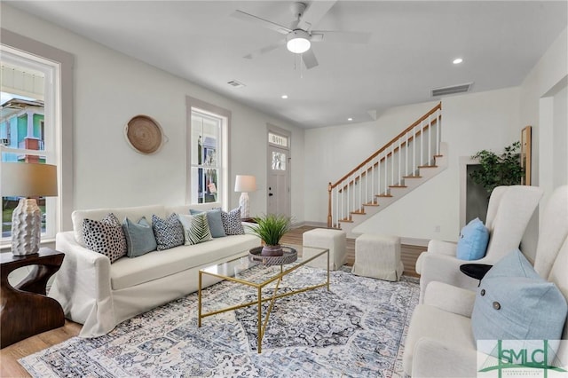 living room with recessed lighting, wood finished floors, visible vents, and stairs