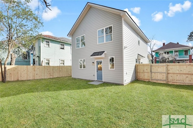 rear view of property with a fenced backyard and a yard