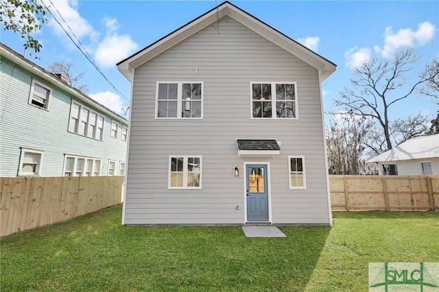 rear view of property featuring a yard and a fenced backyard