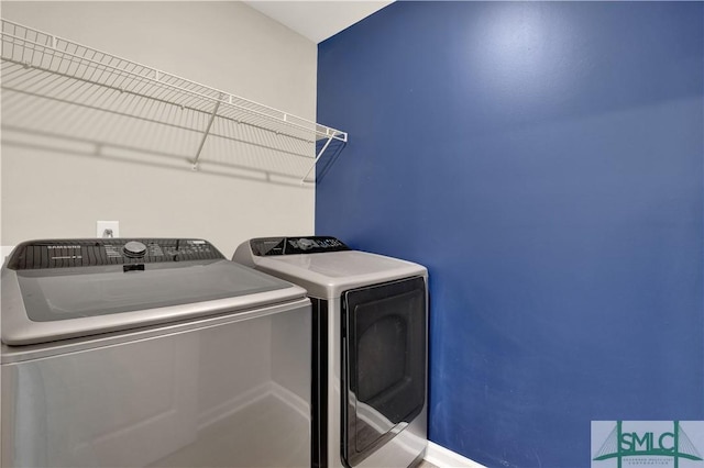 washroom featuring laundry area, washer and clothes dryer, and baseboards