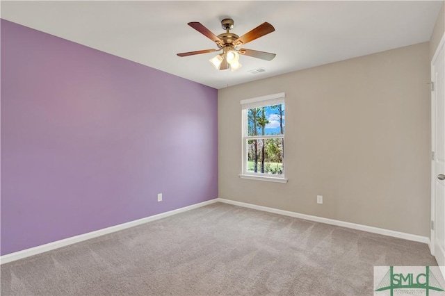 carpeted spare room with visible vents, a ceiling fan, and baseboards