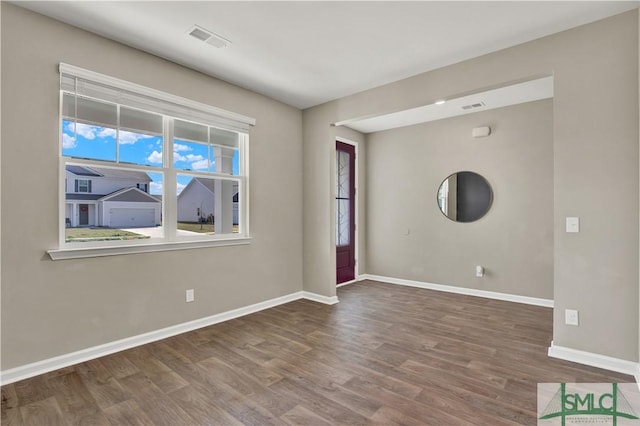 spare room featuring wood finished floors, visible vents, and baseboards