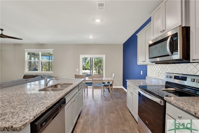 kitchen with tasteful backsplash, visible vents, appliances with stainless steel finishes, open floor plan, and a sink