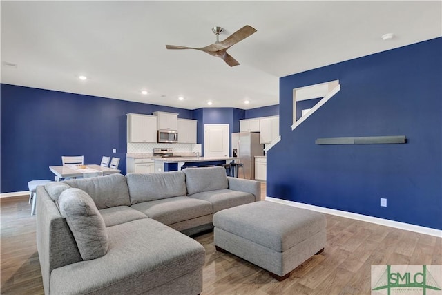 living area with light wood finished floors, recessed lighting, a ceiling fan, and baseboards