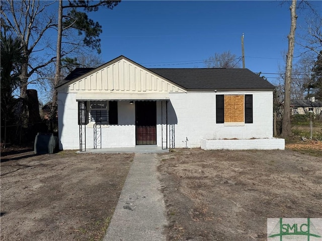 bungalow-style home with board and batten siding, concrete block siding, and a shingled roof