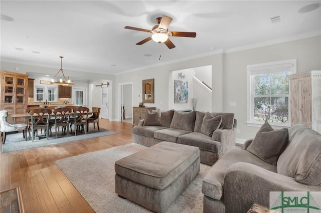 living area featuring ornamental molding, light wood-type flooring, and visible vents