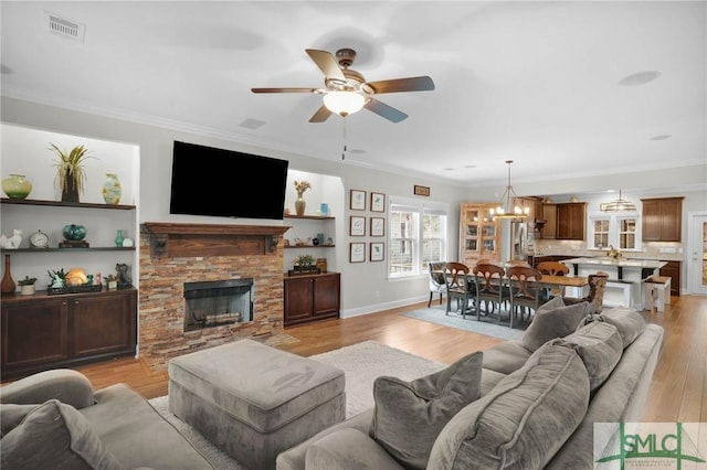 living room with ornamental molding, light wood-type flooring, a fireplace, and visible vents