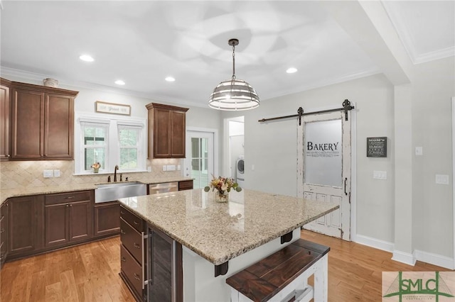 kitchen featuring a barn door, dishwasher, light wood-style flooring, wine cooler, and a sink