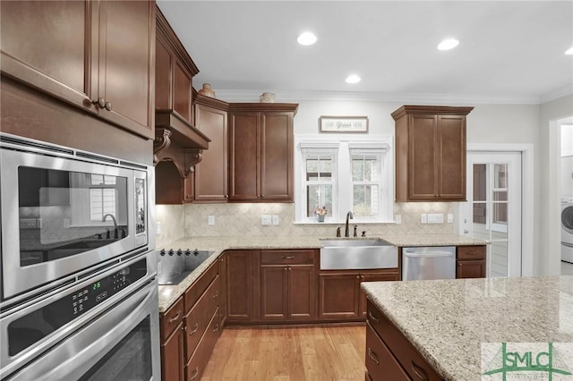 kitchen with appliances with stainless steel finishes, crown molding, a sink, and tasteful backsplash