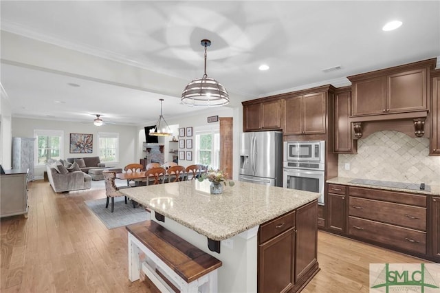 kitchen with light wood-style floors, appliances with stainless steel finishes, a breakfast bar, and backsplash