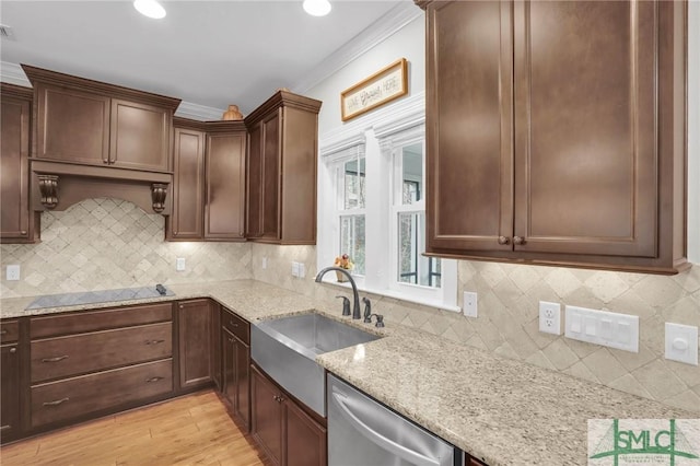 kitchen with black electric stovetop, a sink, light wood-style floors, light stone countertops, and dishwasher