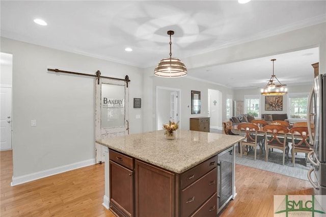 kitchen with light wood-style flooring, a barn door, ornamental molding, freestanding refrigerator, and beverage cooler