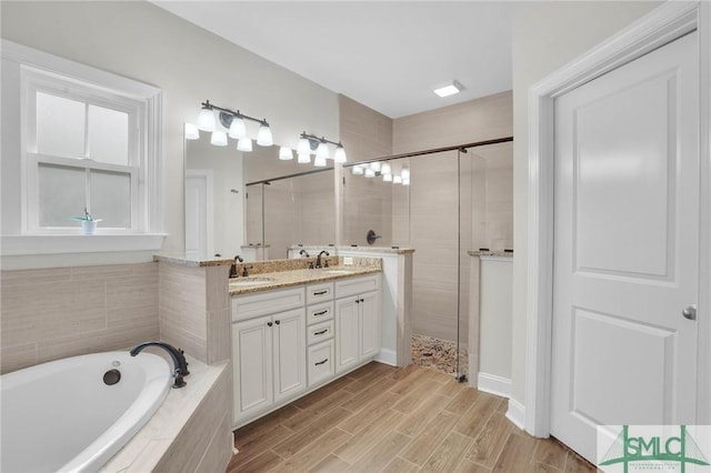 full bathroom with double vanity, a stall shower, wood tiled floor, a sink, and a bath