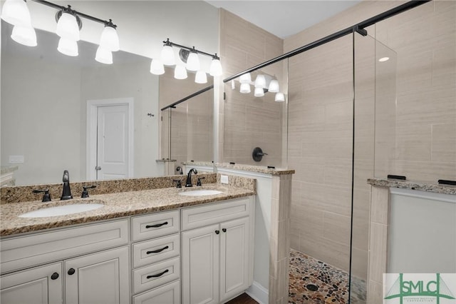 bathroom with a stall shower, a sink, and double vanity