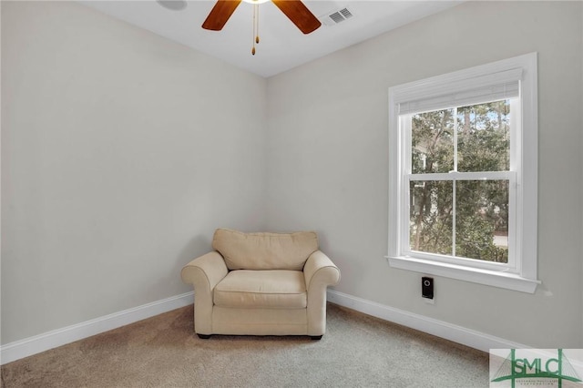 living area featuring carpet floors, visible vents, baseboards, and ceiling fan