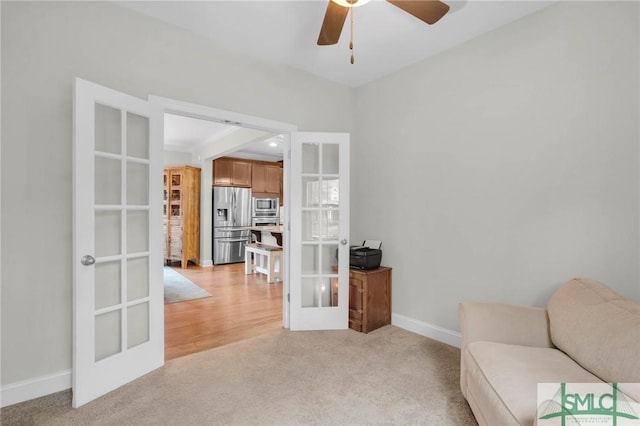 sitting room with ceiling fan, baseboards, light colored carpet, and french doors