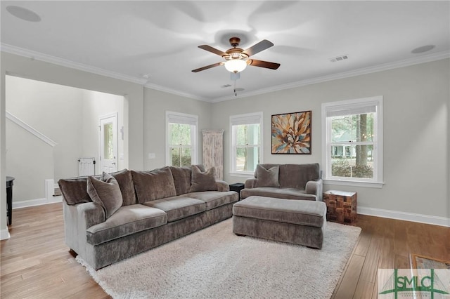 living room with ornamental molding, wood finished floors, visible vents, and baseboards